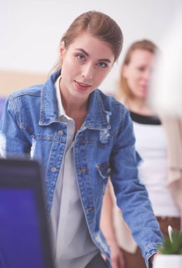 Masanın yanında duran iki genç kadın enstrüman, plan ve dizüstü bilgisayarla.