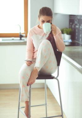 modern mutfakta otururken cep telefonu kullanan kadın.