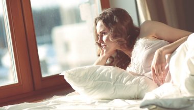 Pencere yakınındaki erken sabah yatakta yatan kadın.