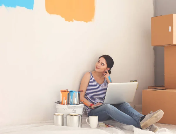 Portrait de jeune femme tout en peignant un nouvel appartement, assis avec ordinateur portable. Jeune femme avec ordinateur portable — Photo