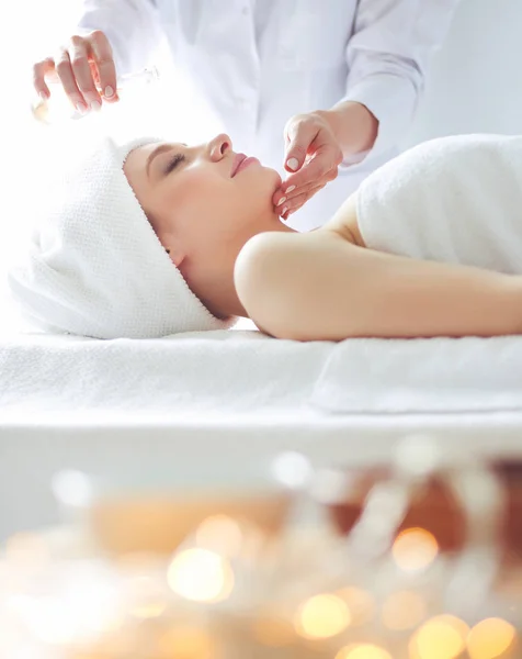 Mujer joven acostada en una mesa de masaje, relajándose con los ojos cerrados. Una mujer. Salón de spa — Foto de Stock