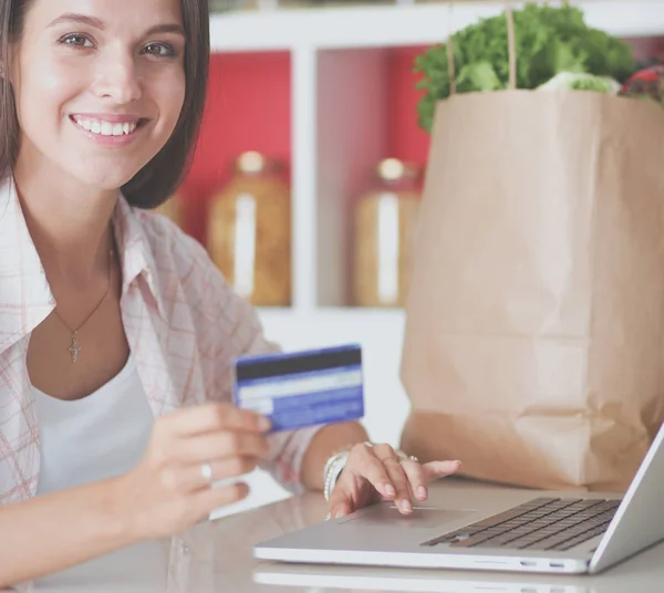 Mujer sonriente compras en línea utilizando tableta y tarjeta de crédito en la cocina. Mujer sonriente — Foto de Stock