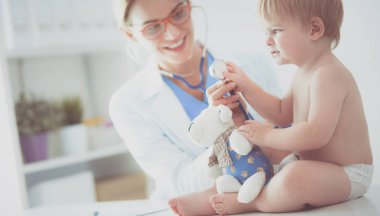 Kadın doktor, klinikte steteskoplu bir çocuğu dinliyor.