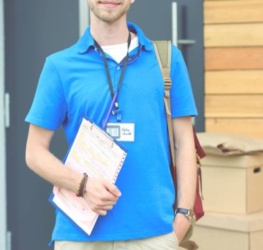 Mavi üniformalı gülümseyen kurye servis konseptine paket kutusu teslim eden teslimatçı. Mavi üniformalı gülümseyen teslimatçı.