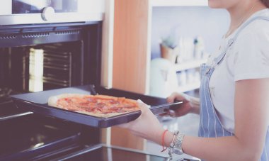 Mutlu genç bayan evde pizza pişiriyor.