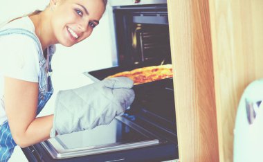 Mutlu genç bayan evde pizza pişiriyor.
