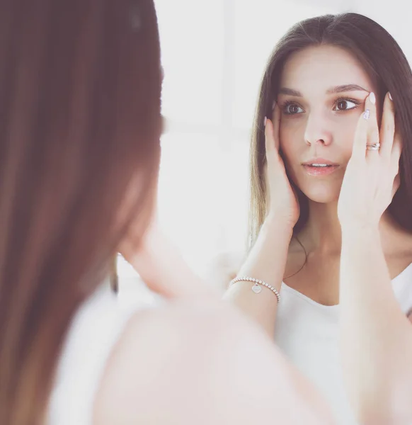 Молодая женщина смотрит на себя отражение в зеркале дома . — стоковое фото