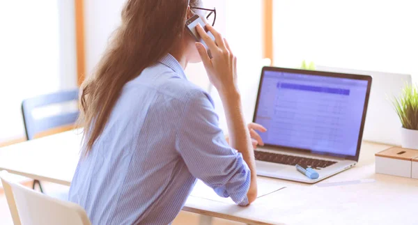 美しい若いビジネスマンの女性がオフィスの机に座って携帯電話で話しています。実業家 — ストック写真