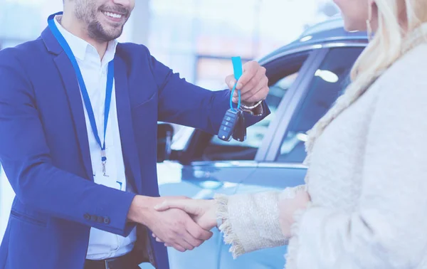Imagen del saludo del concesionario de coches con la mujer feliz en el centro del automóvil — Foto de Stock
