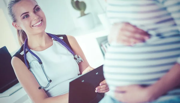 Ung kvinna läkare med stetoskop och tablett talar med gravid kvinna på sjukhus. — Stockfoto
