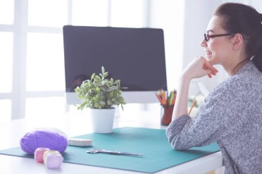 Moda tasarımcıları stüdyoda çalışıyor. Masanın üzerinde oturuyorlar..