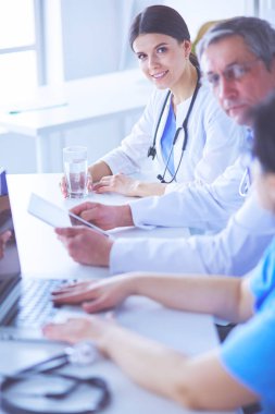 Parlak bir hastane odasında meslektaşlarıyla çalışan gülümseyen bir doktor.