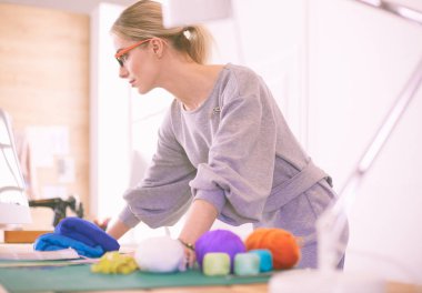 Bir dizüstü bilgisayar kullanarak ve gülümseyen bir genç Asyalı tasarımcı kadın portresi, elbise arka plan olarak astı.