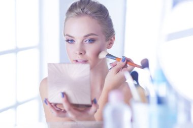 Genç bir kadının banyoya yüz pudrası sürerken fotoğrafı.