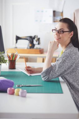 Moda tasarımcıları stüdyoda çalışıyor. Masanın üzerinde oturuyorlar..