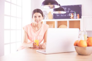 Mutfakta dizüstü bilgisayara benzeyen tariflerle gülümseyen genç bir kadın. Gıda blogcusu kavramı