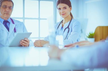 Parlak bir hastane odasında ciddi bir tıbbi ekip bir hastanın hastalığını analiz ediyor.