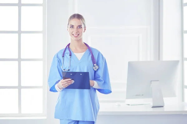 Médecin souriante avec un dossier en uniforme debout — Photo