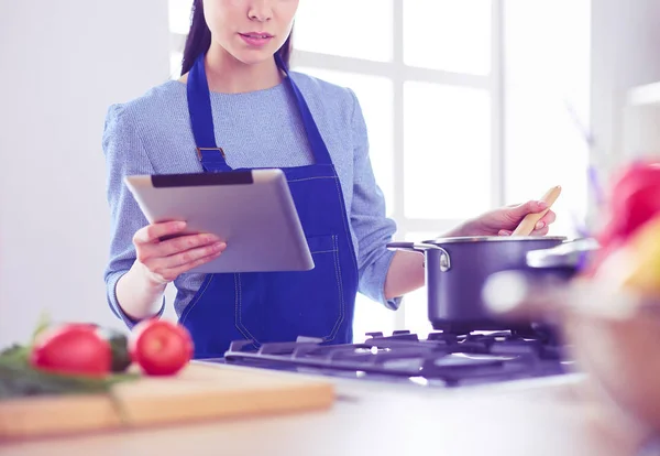 Junge Frau kocht mit Tablet-Computer in ihrer Küche — Stockfoto