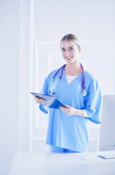 Médico sonriente con una carpeta en uniforme de pie —  Fotos de Stock