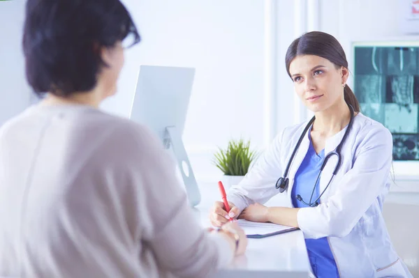 Dokter en patiënt bespreken medische problemen in een ziekenhuis spreekkamer. Doc vult een patiëntenformulier in — Stockfoto