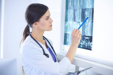 Stetoskop lu genç gülümseyen kadın doktor doktor ofisinde röntgeni işaret ediyor