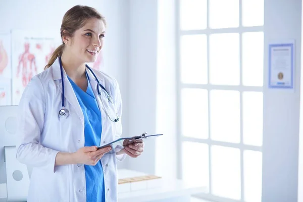Χαμογελαστή γυναίκα γιατρός με ένα φάκελο σε όρθια θέση — Φωτογραφία Αρχείου