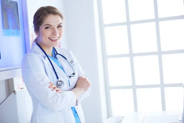 Jovem médica de uniforme branco em pé no escritório de clínicas — Fotografia de Stock