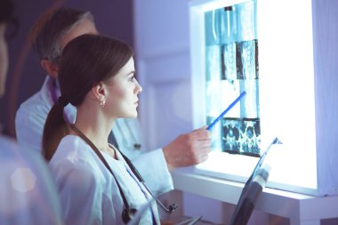 Bir grup doktor bir klinikte röntgenleri inceliyor, teşhis koymayı düşünüyorlar.