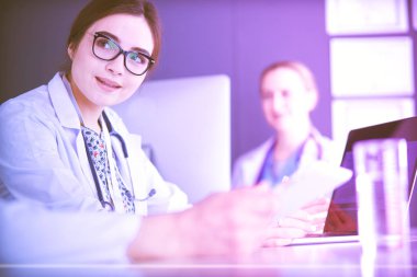 Ciddi bir tıbbi ekip parlak bir ofiste dizüstü bilgisayar kullanıyor.