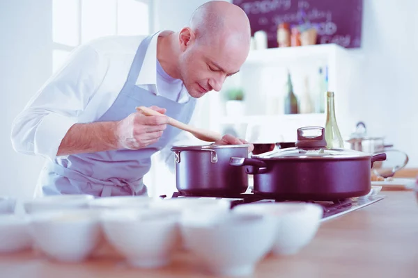 Handsome man is cooking on kitchen and smiling