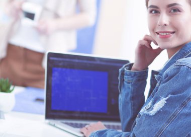 İki genç kadın masada enstrümanlar, planlar ve dizüstü bilgisayarlarla oturuyor..