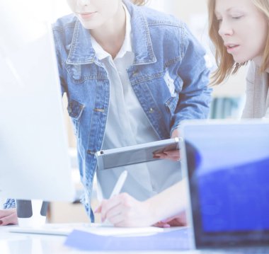 Masanın yanında duran iki genç kadın enstrüman, plan ve dizüstü bilgisayarla.