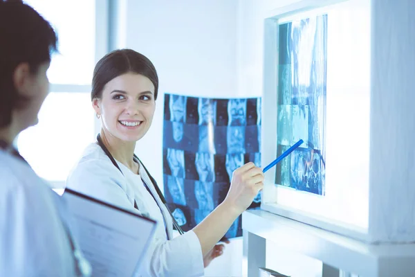 Deux médecins souriants pointant les rayons X dans une salle de consultation de l'hôpital — Photo