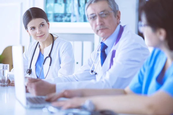 Medico sorridente che utilizza un computer portatile che lavora con i suoi colleghi in una luminosa stanza d'ospedale — Foto Stock