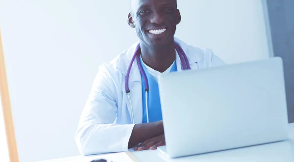 Porträt eines jungen männlichen Arztes, der ein Headset trägt, während er Computer am Schreibtisch in der Klinik benutzt. Arzt. — Stockfoto