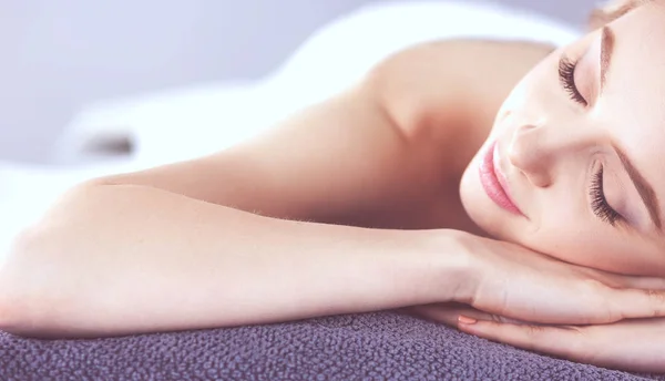 Mujer joven acostada en una mesa de masaje, relajándose con los ojos cerrados. Una mujer. Salón de spa — Foto de Stock