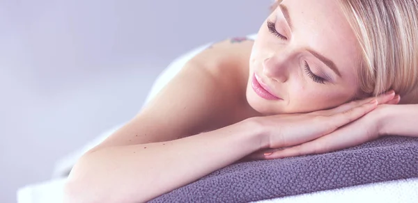 Mujer joven acostada en una mesa de masaje, relajándose con los ojos cerrados. Una mujer. Salón de spa — Foto de Stock