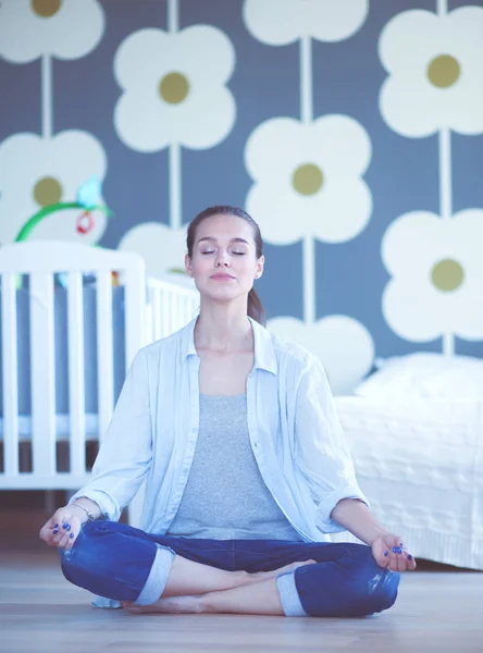 Mujer joven haciendo yoga en casa en la posición de loto. Mujer joven haciendo yoga . — Foto de Stock