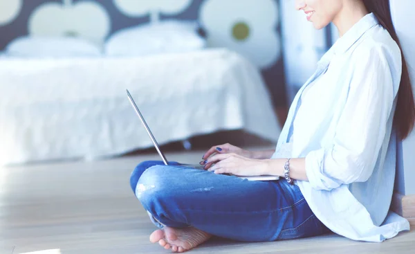 Jonge vrouw zittend op de vloer in de buurt van childrens kinderbed met laptop. Jonge moeder — Stockfoto