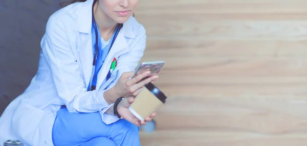 Egy fiatal doktornő ül a telefonjával. Női orvosok. — Stock Fotó