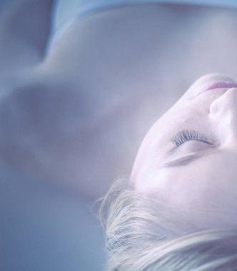 Masaj masasında uzanmış gözleri kapalı rahatlayan genç bir kadın. - Kadın. Spa salonu