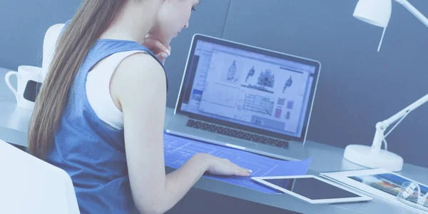 Fiatal nő ül az asztalnál eszközök, terv és laptop. — Stock Fotó