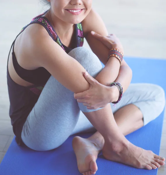 Portræt af den smilende yogakvinde, der sidder på yogamåtten efter træning i yoga studiet. Yoga. Kvinde . - Stock-foto