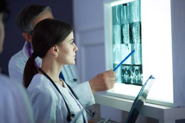 Bir grup doktor bir klinikte röntgenleri inceliyor, teşhis koymayı düşünüyorlar.