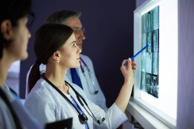 Bir grup doktor bir klinikte röntgenleri inceliyor, teşhis koymayı düşünüyorlar.
