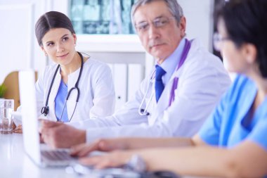 Parlak bir hastane odasında meslektaşlarıyla çalışan gülümseyen bir doktor.