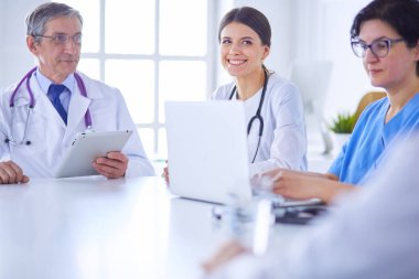 Ciddi bir tıbbi ekip hastaları parlak bir ofiste tartışıyor.