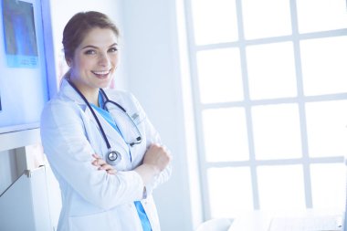 Beyaz üniformalı genç kadın doktor klinikte bekliyor.