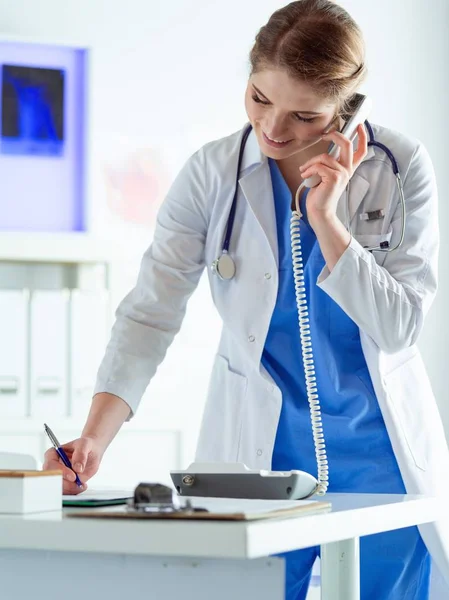 Serious doctor on the phone in her office — Stock Photo, Image